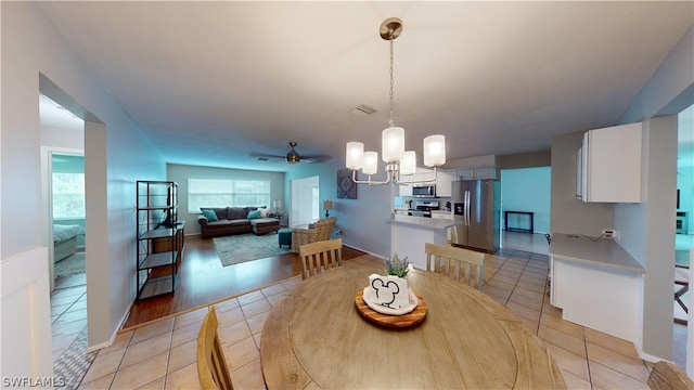 tiled dining room with ceiling fan with notable chandelier