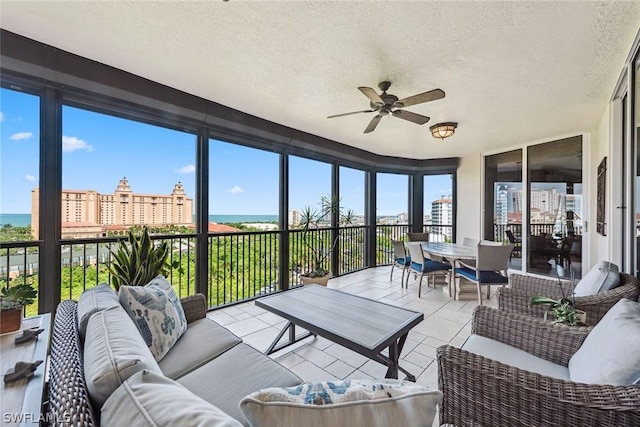 sunroom featuring a water view and ceiling fan