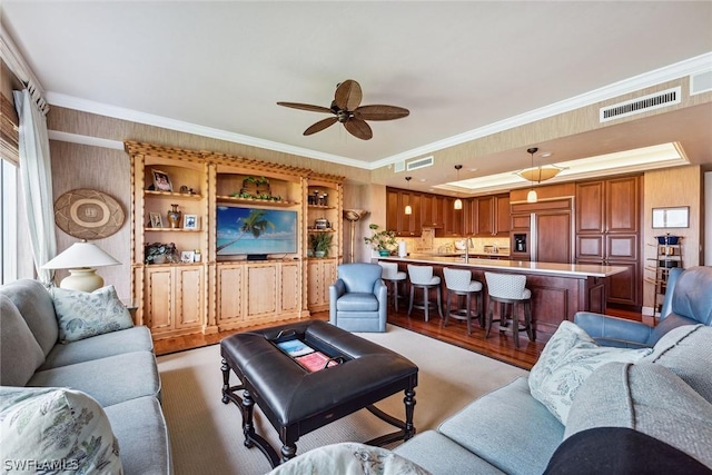 living room with ceiling fan, sink, and crown molding