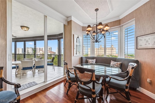 dining space with breakfast area, ornamental molding, a textured ceiling, a notable chandelier, and hardwood / wood-style floors