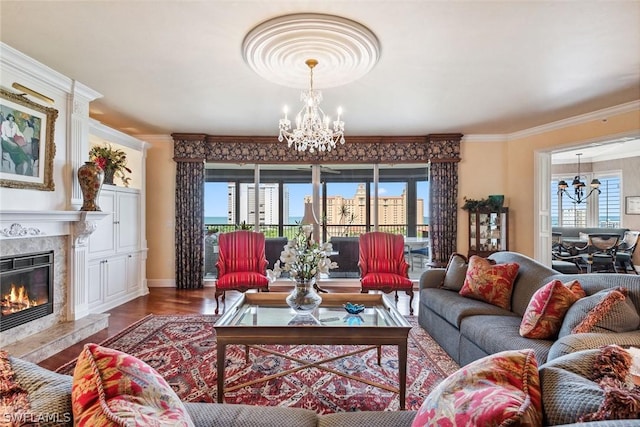 living room with a high end fireplace, hardwood / wood-style floors, an inviting chandelier, and plenty of natural light