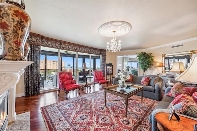 living room featuring dark hardwood / wood-style floors, a premium fireplace, crown molding, and a chandelier