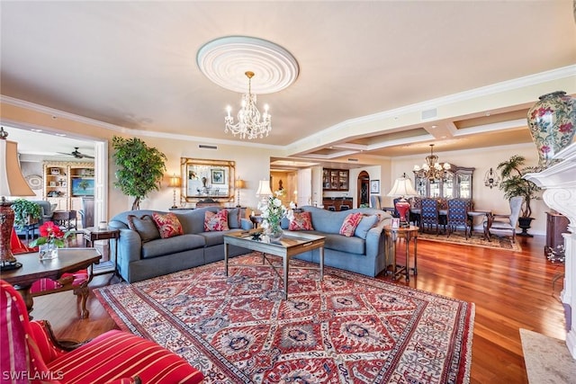 living room featuring coffered ceiling, ceiling fan with notable chandelier, crown molding, hardwood / wood-style flooring, and a premium fireplace