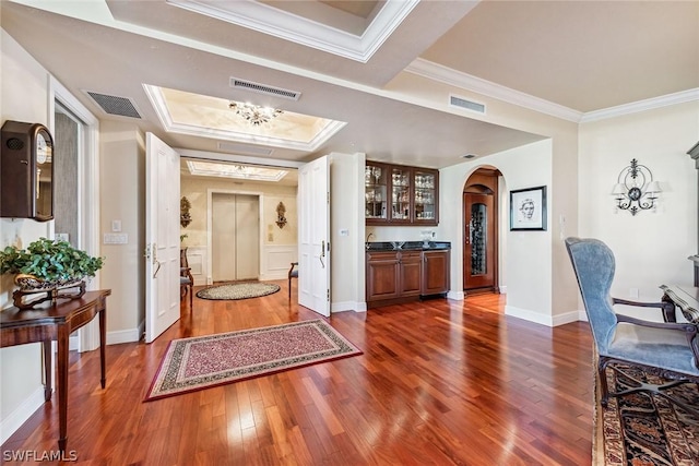 interior space with dark wood-type flooring, crown molding, and a tray ceiling