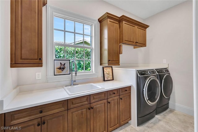 clothes washing area with cabinet space, a sink, baseboards, and separate washer and dryer