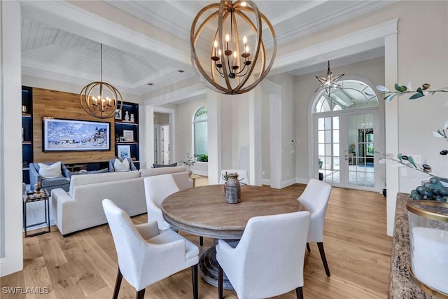 dining room featuring light wood-style flooring, crown molding, a tray ceiling, and a notable chandelier