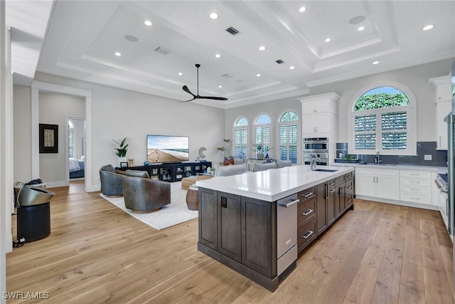 kitchen with dark brown cabinetry, white cabinetry, a tray ceiling, and a sink