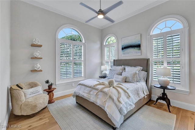 bedroom with a ceiling fan, baseboards, wood finished floors, and ornamental molding