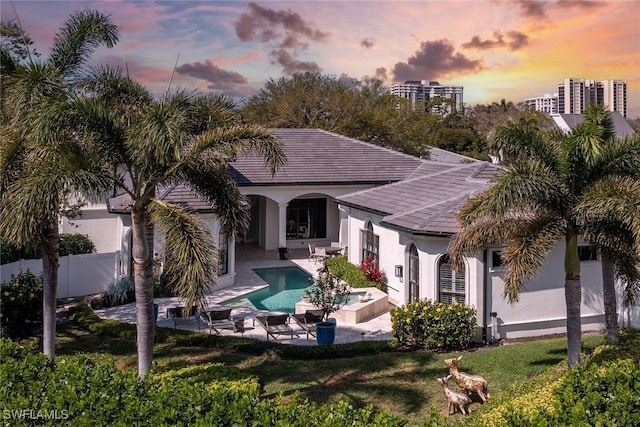 rear view of property with fence, a lawn, a fenced in pool, stucco siding, and a patio area