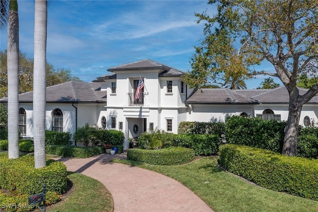 view of front of home featuring a balcony, a tiled roof, and stucco siding