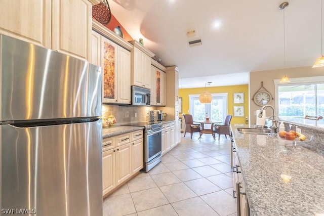 kitchen featuring hanging light fixtures, sink, light stone countertops, light tile patterned floors, and appliances with stainless steel finishes