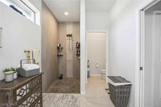 bathroom featuring tile patterned flooring, a tile shower, and toilet