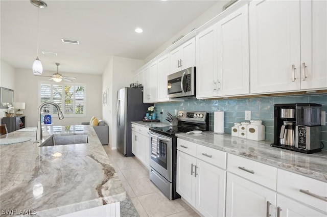 kitchen with light stone countertops, appliances with stainless steel finishes, sink, pendant lighting, and white cabinetry