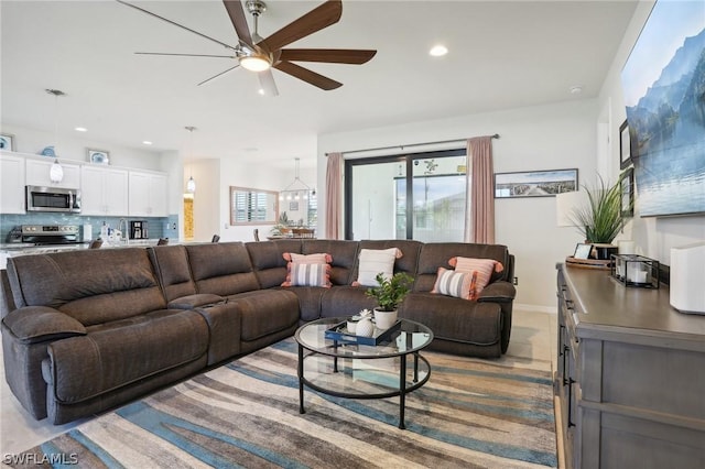 living room with light tile patterned floors and ceiling fan with notable chandelier