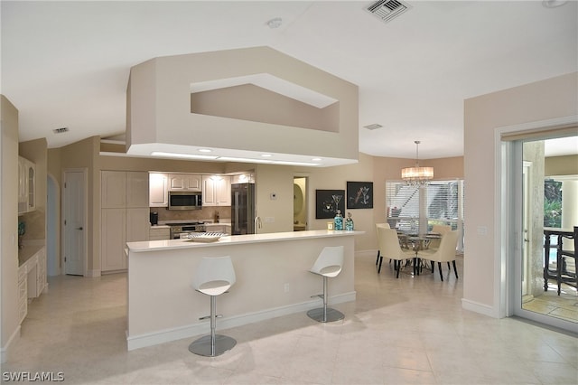 kitchen featuring appliances with stainless steel finishes, tasteful backsplash, an inviting chandelier, hanging light fixtures, and a breakfast bar area