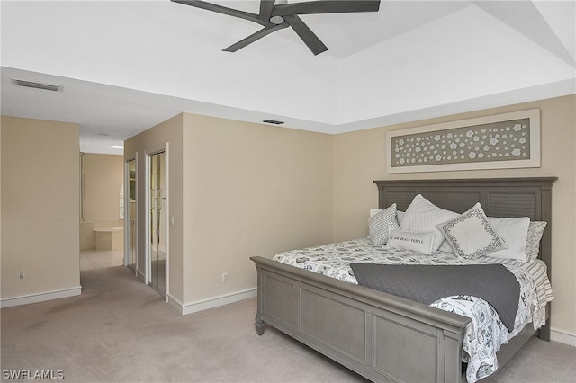 bedroom with connected bathroom, light colored carpet, and ceiling fan