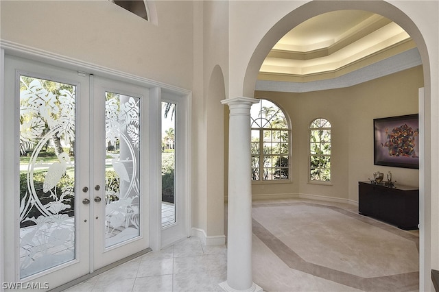 tiled entrance foyer featuring french doors, a tray ceiling, and a wealth of natural light