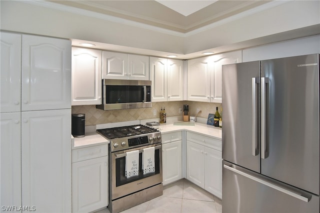 kitchen featuring tasteful backsplash, stainless steel appliances, crown molding, light tile patterned floors, and white cabinetry