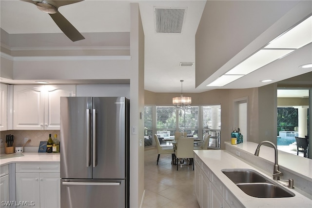 kitchen with white cabinets, hanging light fixtures, sink, and stainless steel refrigerator