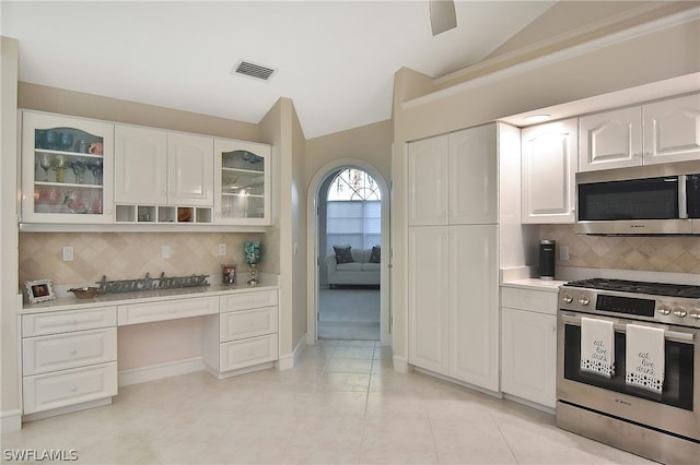 kitchen with tasteful backsplash, white cabinetry, vaulted ceiling, and appliances with stainless steel finishes