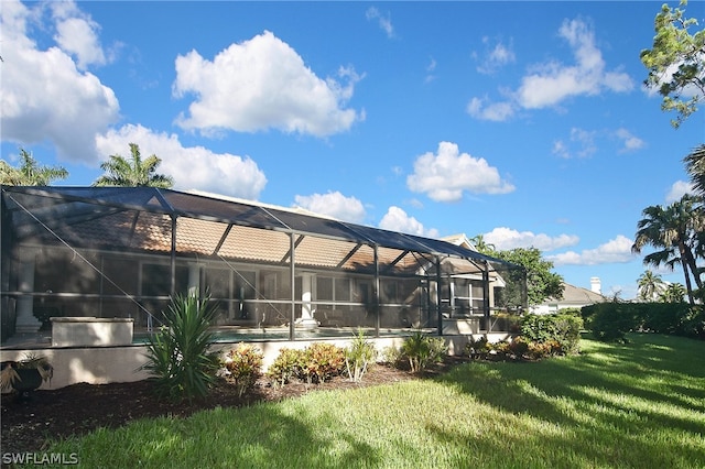 back of property featuring glass enclosure and a yard