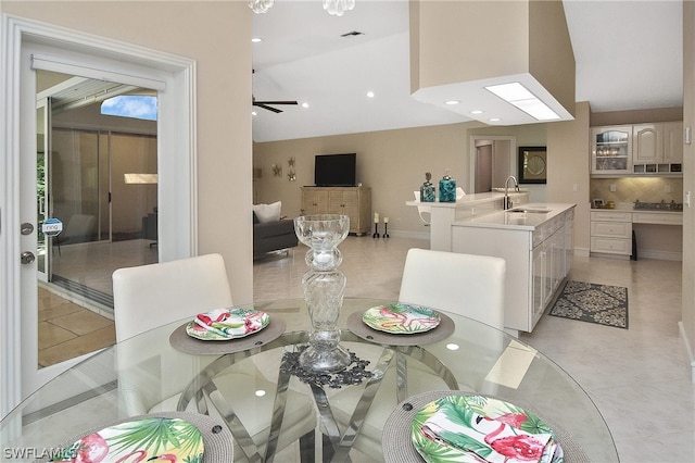 tiled dining room with ceiling fan, sink, and vaulted ceiling