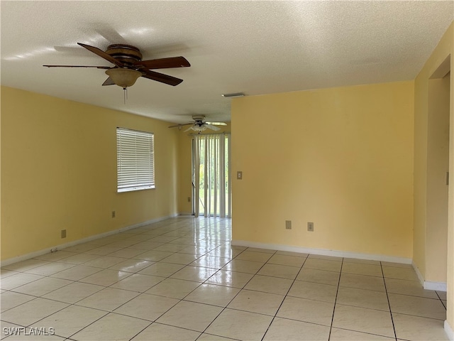 empty room featuring ceiling fan, light tile patterned floors, and a textured ceiling