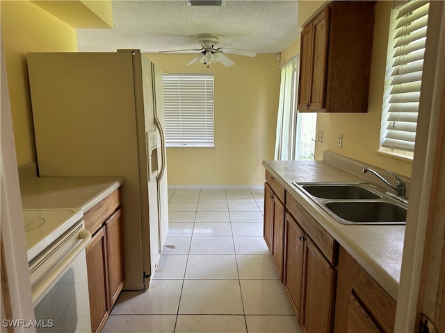 kitchen featuring ceiling fan, white appliances, sink, light tile patterned floors, and a textured ceiling