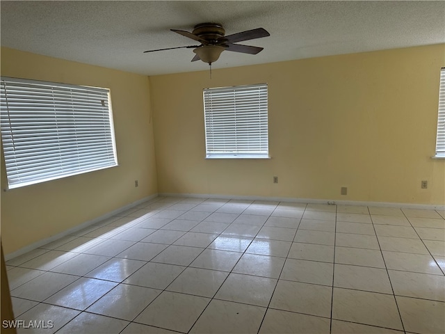 tiled empty room featuring ceiling fan and a textured ceiling