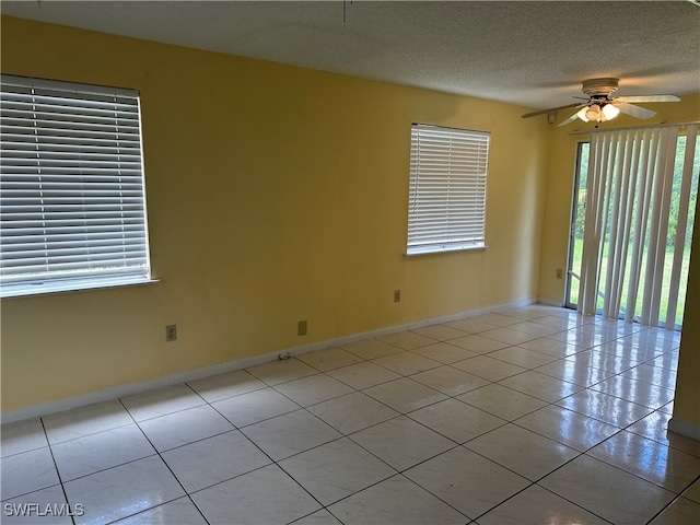 empty room featuring ceiling fan, a textured ceiling, and light tile patterned floors