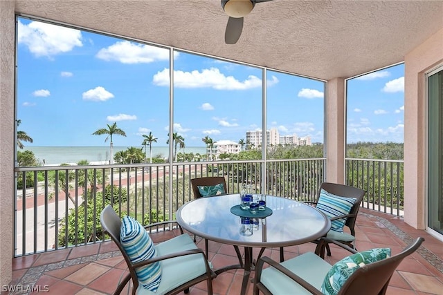 sunroom featuring ceiling fan and a water view