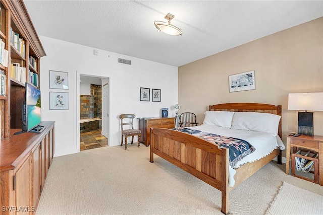 bedroom with baseboards, visible vents, light colored carpet, ensuite bathroom, and a textured ceiling