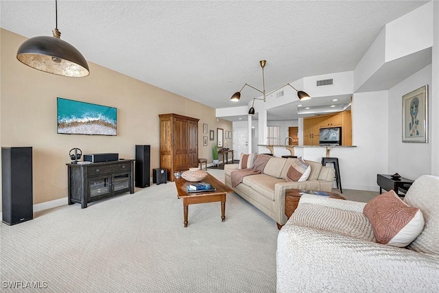 living room featuring baseboards, visible vents, a textured ceiling, and light colored carpet