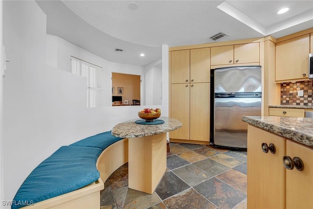 kitchen with backsplash, stone tile flooring, visible vents, and stainless steel appliances