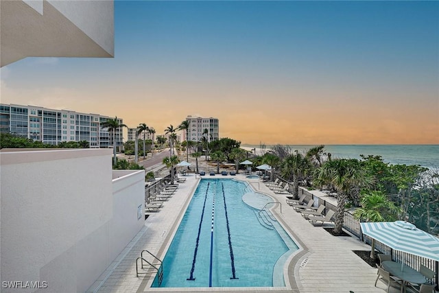 pool at dusk featuring a community pool