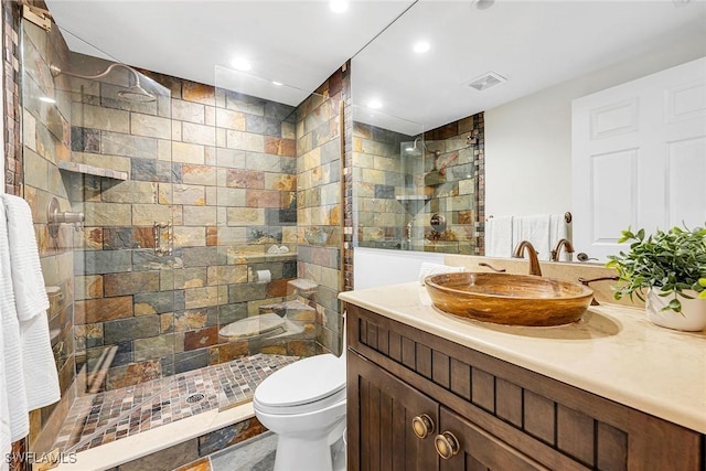 bathroom with visible vents, vanity, a walk in shower, and toilet