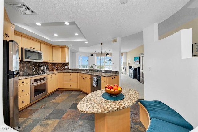 kitchen featuring a sink, stone tile floors, light brown cabinetry, appliances with stainless steel finishes, and visible vents