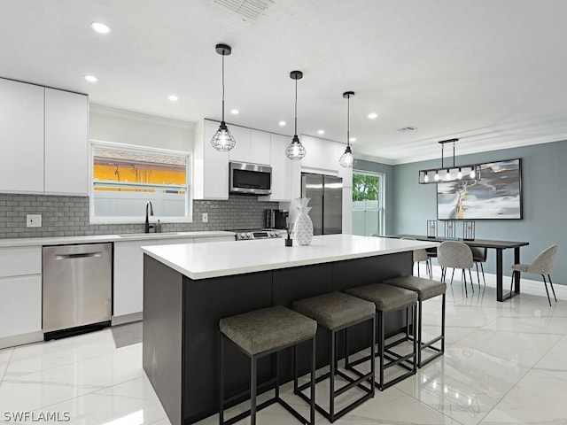 kitchen with pendant lighting, a center island, white cabinetry, and stainless steel appliances