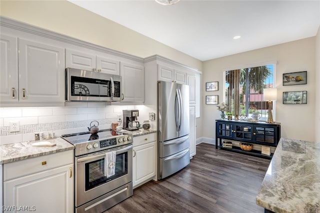 kitchen with stainless steel appliances, dark wood-type flooring, white cabinetry, backsplash, and light stone countertops