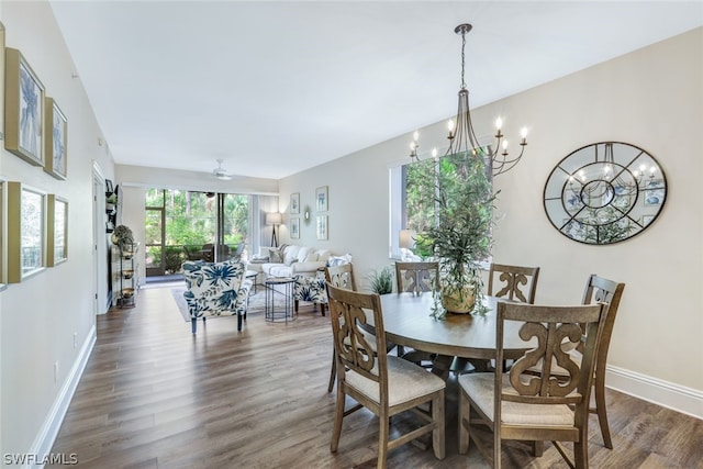 dining room with dark wood-type flooring, a notable chandelier, and baseboards