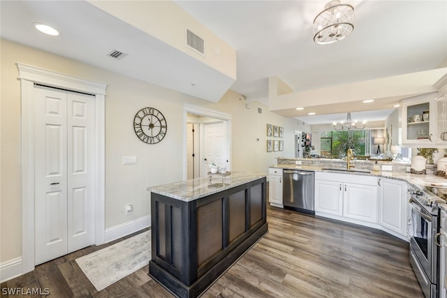 kitchen featuring a chandelier, stainless steel appliances, a sink, white cabinets, and glass insert cabinets