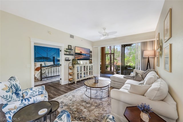 living area featuring dark wood-style flooring, visible vents, ceiling fan, and baseboards