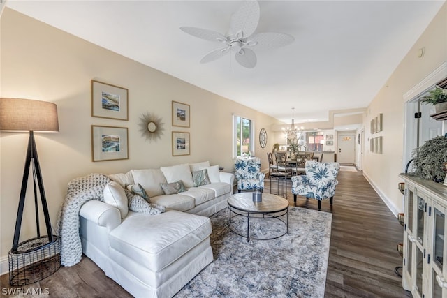 living area featuring dark wood-type flooring, baseboards, and ceiling fan with notable chandelier