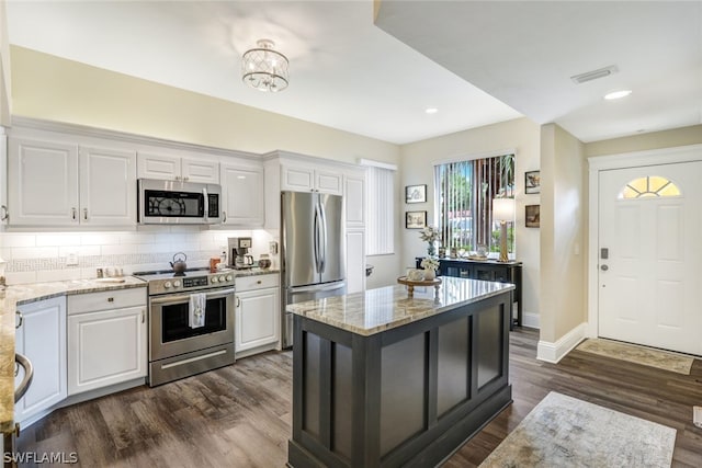 kitchen with stainless steel appliances, white cabinetry, and light stone counters