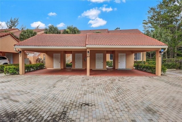 rear view of property featuring a tile roof and stucco siding