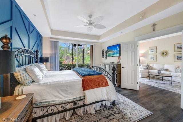 bedroom featuring a tray ceiling, dark wood finished floors, and ceiling fan