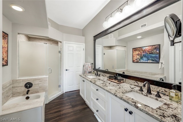 full bathroom featuring double vanity, a stall shower, a sink, and wood finished floors