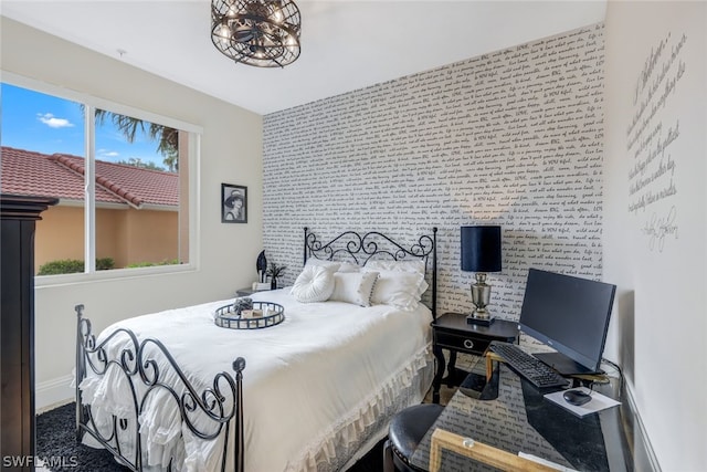 bedroom with brick wall, an accent wall, baseboards, and a notable chandelier