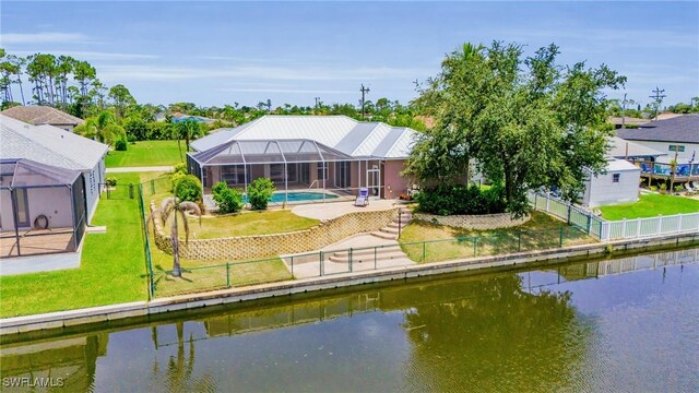 back of property featuring a yard, a water view, and glass enclosure