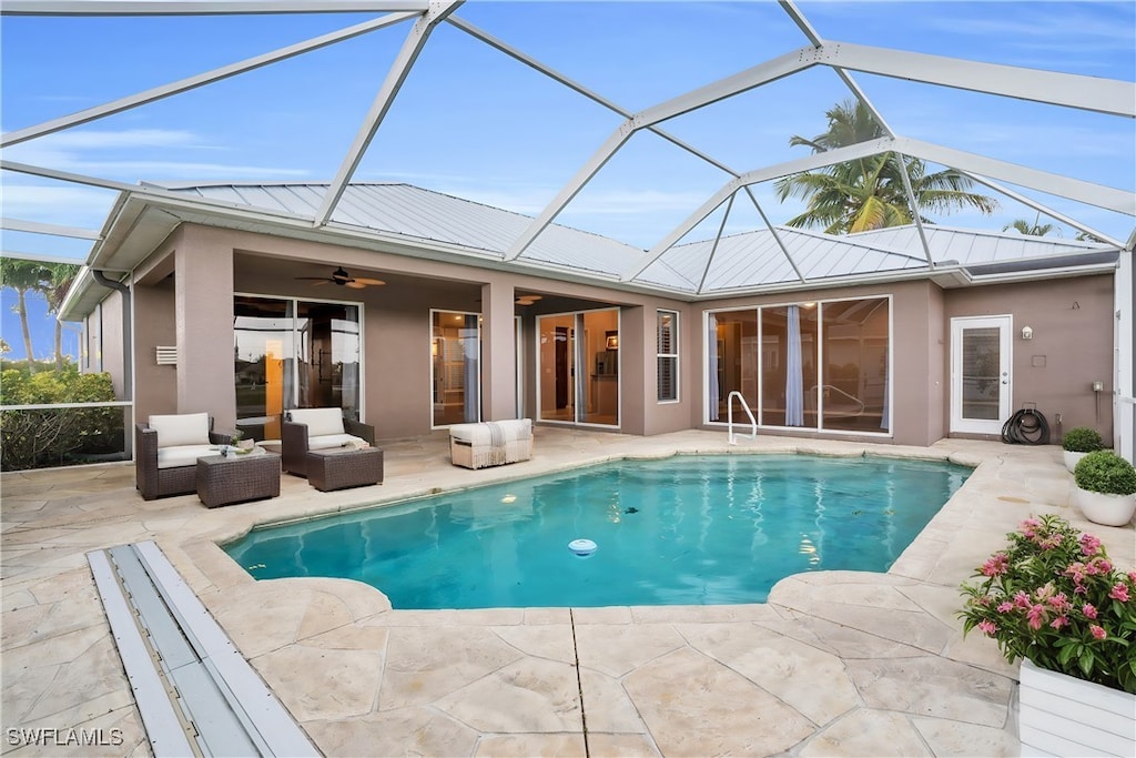 view of pool featuring an outdoor hangout area, a patio area, ceiling fan, and glass enclosure